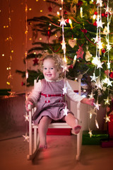 Wall Mural - Little girl in rocking chair under Christmas tree