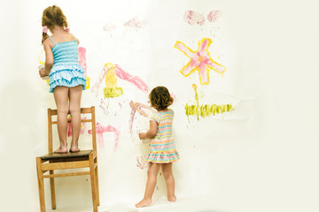 two cute young child girls painting over white