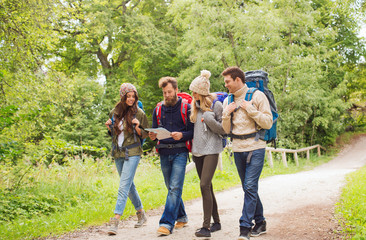 Wall Mural - group of smiling friends with backpacks hiking