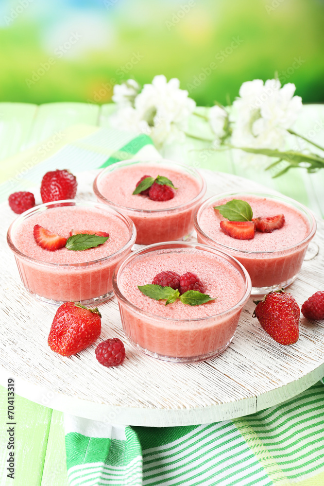Delicious berry mousse in bowls on table on bright background
