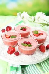 Wall Mural - Delicious berry mousse in bowls on table on bright background