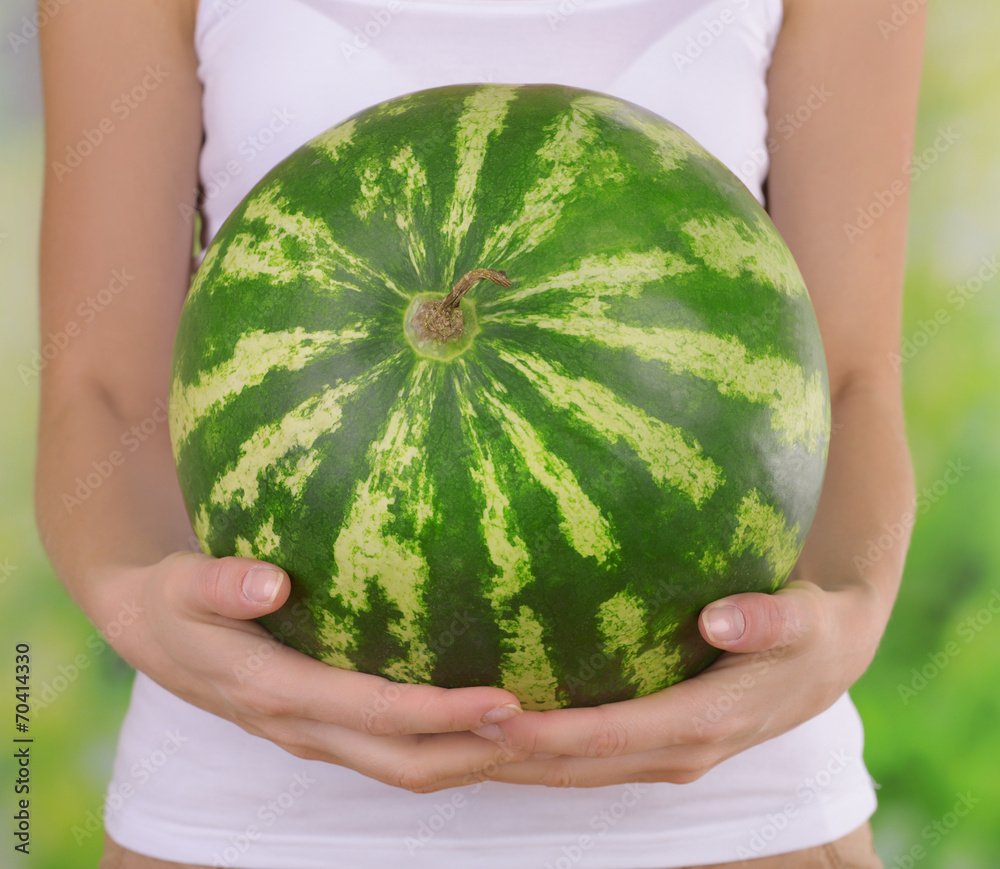 Woman holding watermelon on bright background