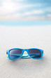 blue plastic sunglasses lying on the beach