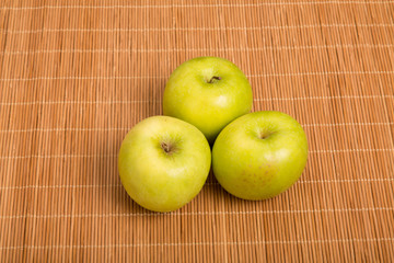 Wall Mural - Three Granny Smith Apples on a Bamboo Placemat