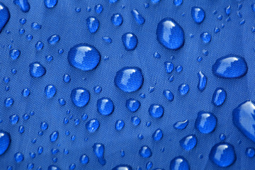 Closeup of rain drops on a blue umbrella