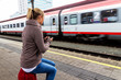 Frau wartet auf Zug und schreibt SMS