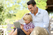 Daddy And Son Playing With Tablet Outside