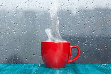 Wall Mural - Steaming coffee cup on a rainy day window background