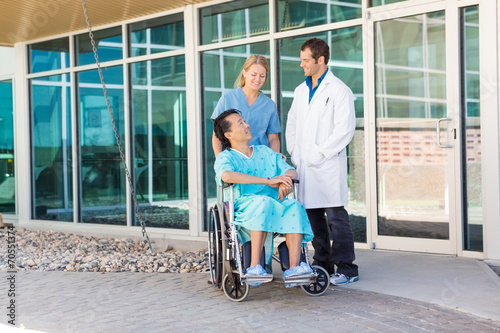 Foto Krankenschwester And Doctor, die Patienten auf Rollstuhl außerhalb Hospit betrac