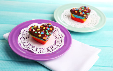 Wall Mural - Delicious rainbow cakes on plates, on color wooden background