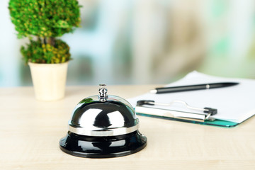 Reception bell on desk, on bright background