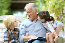 Senior Man Reading Book With Grandkids
