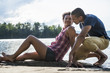 © Mint Images - A couple close together by a lake in summer.