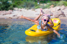 Little Girl Enjoying Swimming In Yellow Kayak In The Clear