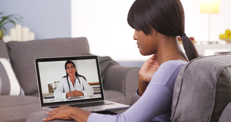 African woman talking with doctor online