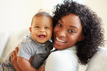 smiling mother playing with baby son at home