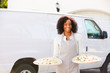 © Monkey Business - Woman Delivering Pizza Standing In Front Of Van