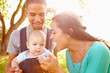 © Monkey Business - Family With Baby Son In Carrier Walking Through Park
