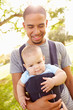© Monkey Business - Father With Son In Baby Carrier Walking Through Park