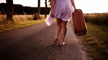 Woman Carrying Suitcase On Rural Road