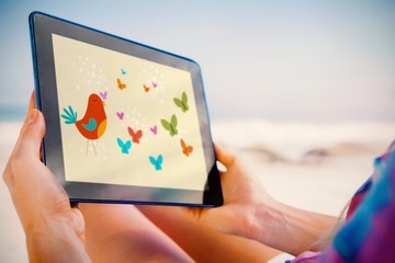 Poster - Woman sitting on beach in deck chair using tablet pc
