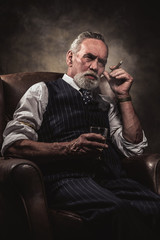 Wall Mural - In chair sitting senior business man with cigar and whisky. Gray