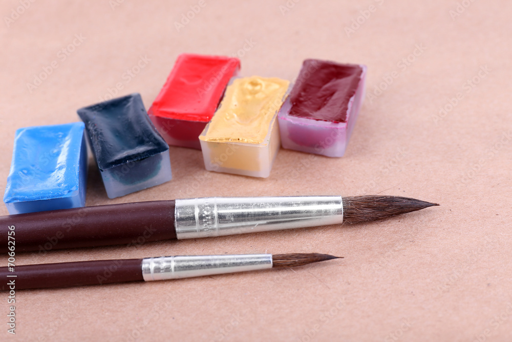 Watercolor paint cubes and brushes on beige background