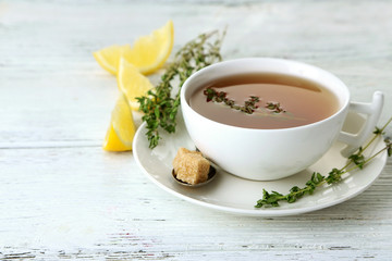 Fototapete - Cup of tasty herbal tea with thyme and lemon on wooden table