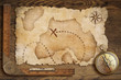 aged treasure map, ruler and old bronze compass on wooden table