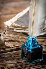 Wall Mural - White feather on blue inkwell and old book