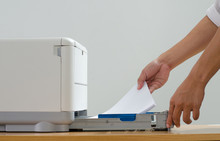 Male Hand Holding Paper Sheets Into Printer Tray In Office.
