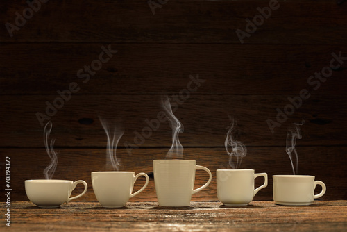 Fototapeta na wymiar Variety of cups of coffee with smoke on wooden background