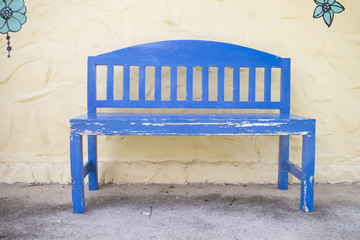 Blue wooden bench in front of pale yellow wall