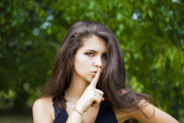 Woman has put forefinger to lips as sign of silence