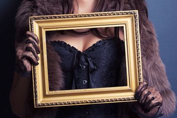 Wall Mural - woman wearing corset and fur and holding vintage golden frame