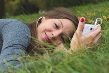 Brunette Woman Listening Music In The Park On Her Smart Phone