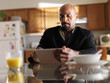 © Joshua Resnick - mature african man with tablet in kitchen and breakfast