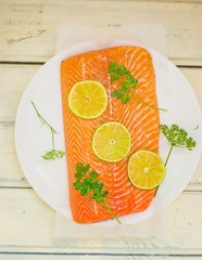 fresh, crude fillet of a salmon with slices of a lime and greens