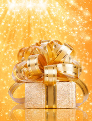 Gift box in gold wrapping paper on a beautiful abstract backgrou