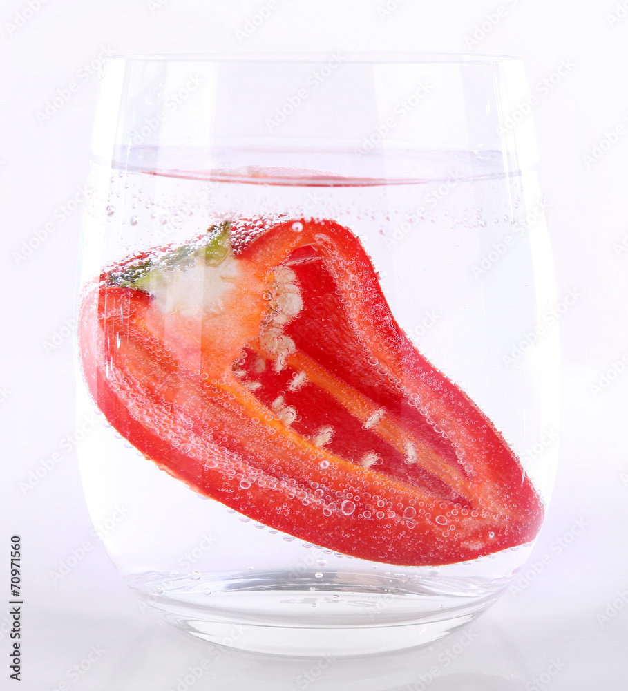 Red pepper in glass of water isolated on white