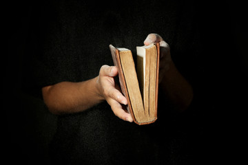 Woman holding very old book with dust, on dark background