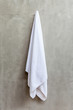 Hanging white towel draped on exposed concrete wall in the bathr