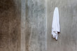 Hanging white towel draped on exposed concrete wall in the bathr