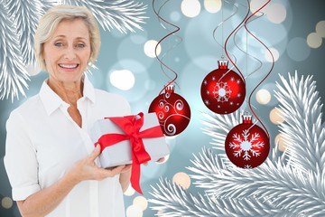 Poster - Composite image of mature woman holding gift