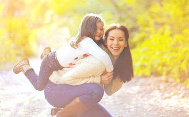 Happy mother and child having fun in autumn park