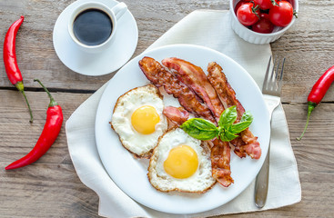 Wall Mural - Fried eggs with bacon on the wooden table