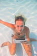 © Netfalls - Young woman undewater with tablet computer