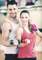 Canvas Print - two smiling people working out with dumbbells