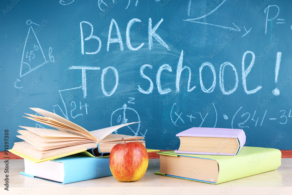 School supplies on table on blackboard background