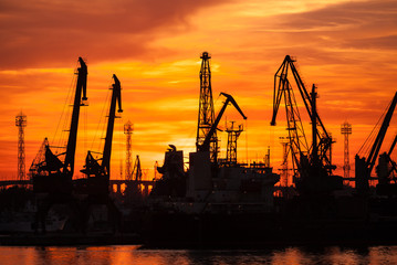  Silhouettes of cranes and cargo ships in port of Varna at sunset